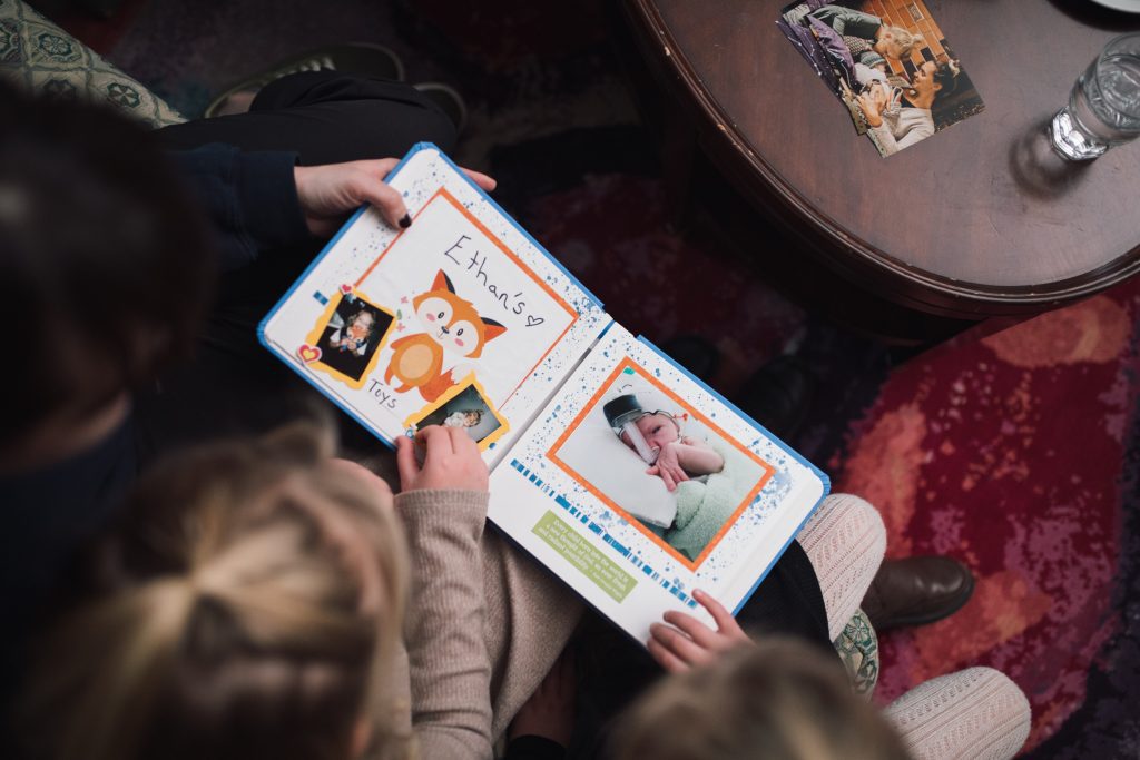 Members of the Van Oosterom family look through their Precious Pictures scrapbook together with Canuck Place Counsellor Natasha Zacher.