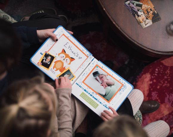 Members of the Van Oosterom family look through their Precious Pictures scrapbook together with Canuck Place Counsellor Natasha Zacher.