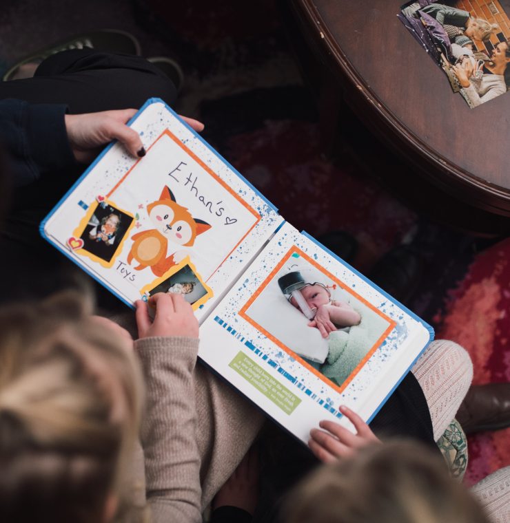 Members of the Van Oosterom family look through their Precious Pictures scrapbook together with Canuck Place Counsellor Natasha Zacher.